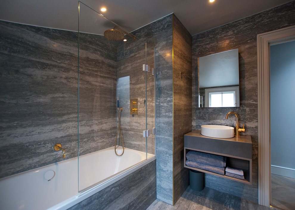Inspiration for a contemporary master bathroom in London with a drop-in tub, a shower/bathtub combo, gray tile, ceramic tile, grey walls, grey floor, open cabinets, grey cabinets and a vessel sink.