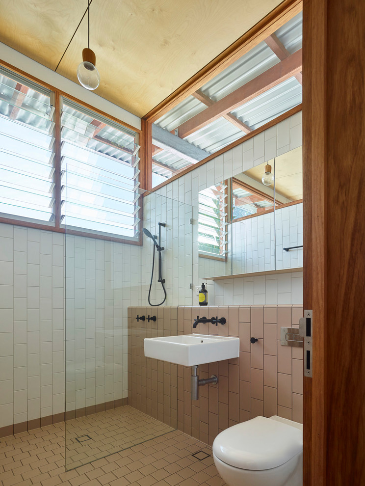 This is an example of a small contemporary master bathroom in Brisbane with glass-front cabinets, an open shower, a one-piece toilet, white tile, ceramic tile, white walls, ceramic floors, a wall-mount sink, tile benchtops, brown floor and an open shower.
