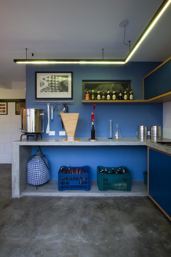 Design ideas for a mid-sized industrial l-shaped seated home bar in Other with a drop-in sink, flat-panel cabinets, blue cabinets, concrete benchtops, blue splashback, concrete floors, grey floor and grey benchtop.