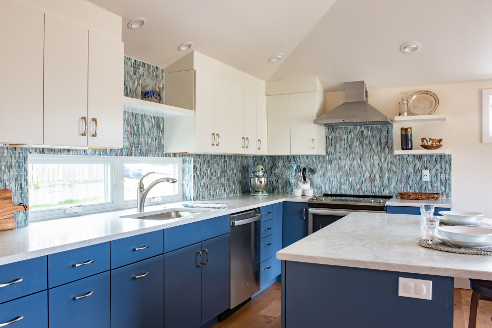 Example of a small beach style l-shaped vaulted ceiling, light wood floor and brown floor eat-in kitchen design in Seattle with an undermount sink, flat-panel cabinets, blue cabinets, blue backsplash, glass tile backsplash, stainless steel appliances, an island and gray countertops