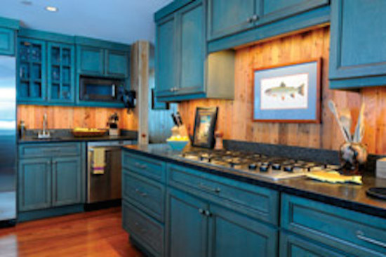 This is an example of a mid-sized eclectic galley separate kitchen in Portland Maine with raised-panel cabinets, blue cabinets, grey splashback, stainless steel appliances, medium hardwood floors, with island and solid surface benchtops.