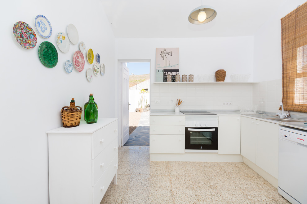 Design ideas for a small mediterranean l-shaped separate kitchen in Other with flat-panel cabinets, white cabinets, white appliances, a drop-in sink, white splashback, subway tile splashback, ceramic floors and no island.