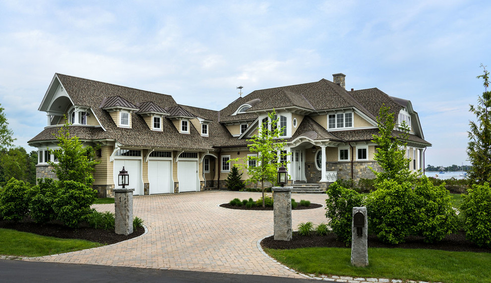 Photo of an expansive beach style two-storey beige exterior in Boston with mixed siding, a hip roof and a shingle roof.