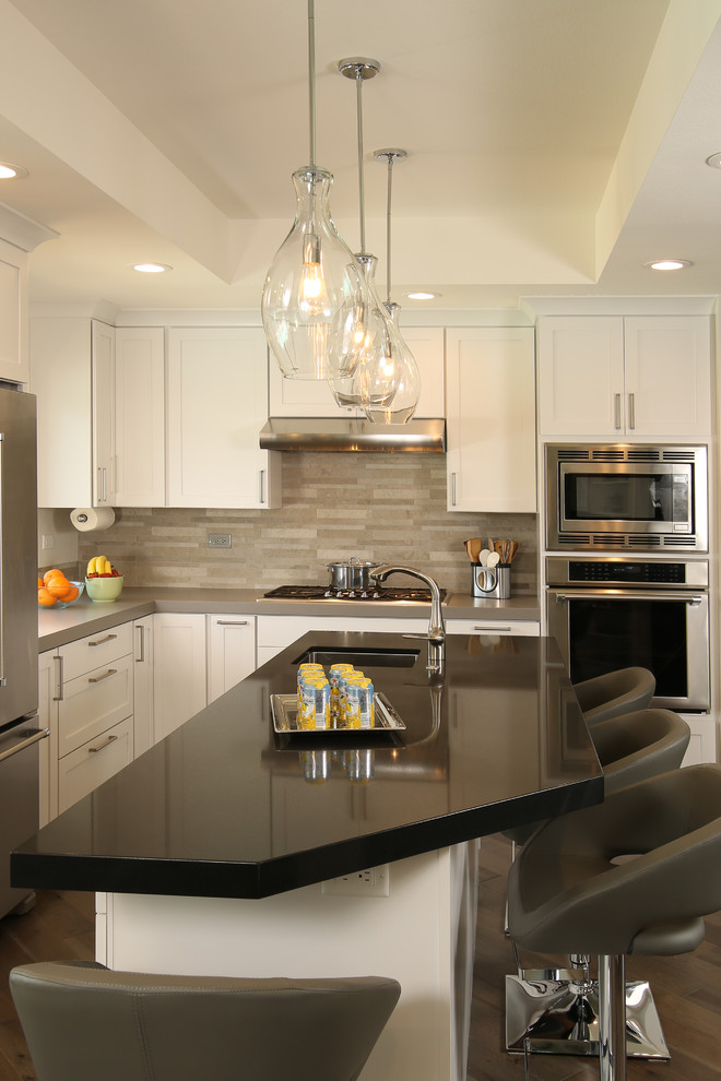 This is an example of a large contemporary l-shaped separate kitchen in San Francisco with a double-bowl sink, shaker cabinets, white cabinets, matchstick tile splashback, stainless steel appliances, dark hardwood floors, with island, brown floor, quartz benchtops, grey splashback and black benchtop.