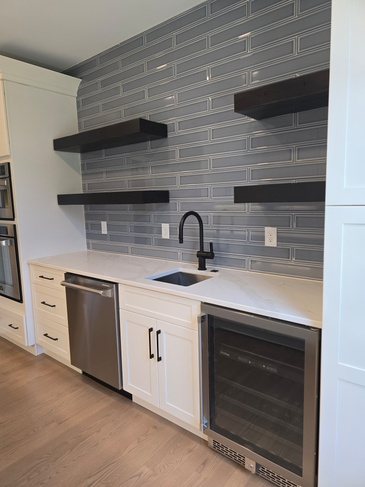Inspiration for a large modern l-shaped medium tone wood floor and brown floor kitchen remodel with shaker cabinets, white cabinets, quartz countertops, gray backsplash, subway tile backsplash, stainless steel appliances, white countertops and an undermount sink