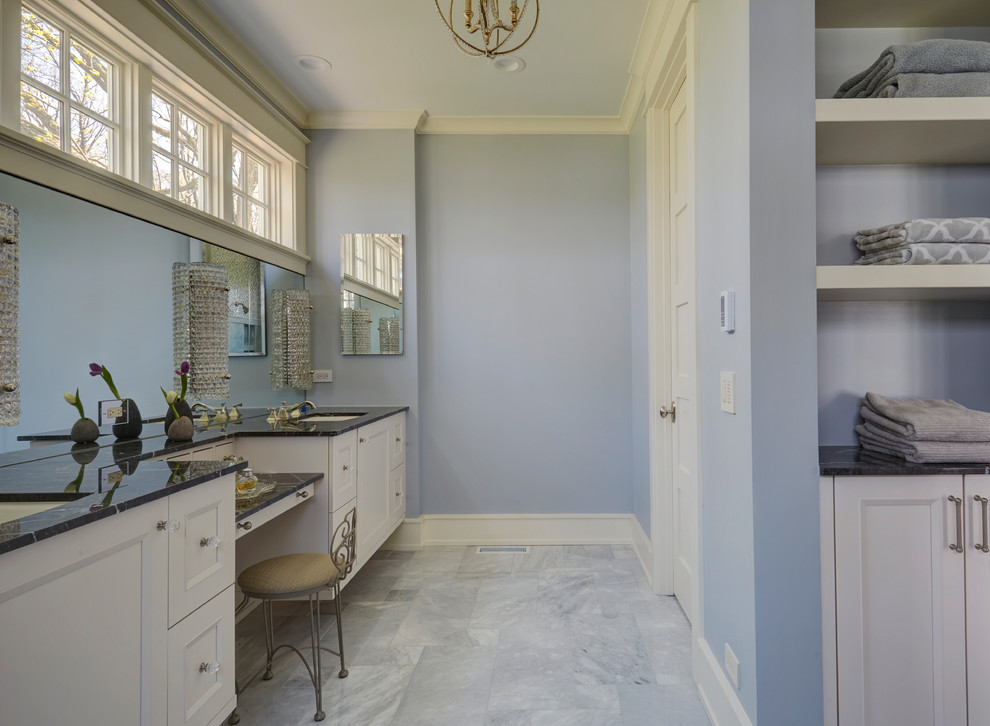 This is an example of a large traditional master bathroom in Chicago with shaker cabinets, white cabinets, blue walls, marble floors, an undermount sink, granite benchtops, grey floor and black benchtops.