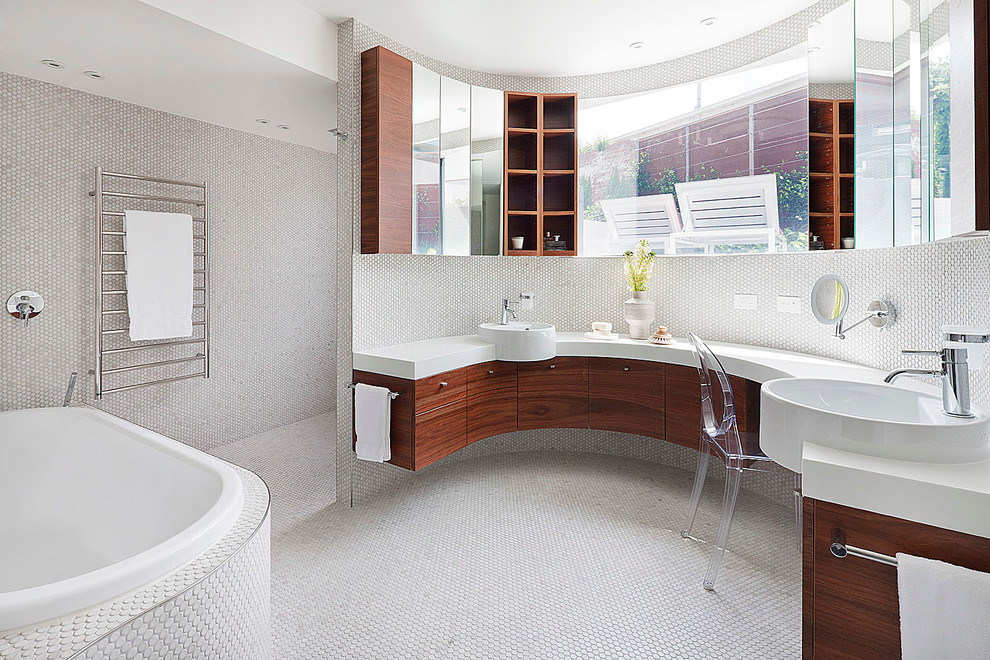 This is an example of a large contemporary master bathroom in Melbourne with flat-panel cabinets, medium wood cabinets, solid surface benchtops, a drop-in tub, an open shower, white tile, mosaic tile, mosaic tile floors and an open shower.