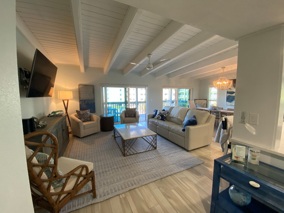 Design ideas for a large beach style open concept family room in Tampa with blue walls, porcelain floors, no fireplace, a wall-mounted tv and beige floor.