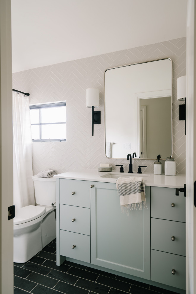 Small transitional kids bathroom in Salt Lake City with shaker cabinets, blue cabinets, an alcove tub, an alcove shower, a one-piece toilet, beige tile, ceramic tile, beige walls, slate floors, a drop-in sink, engineered quartz benchtops, black floor, a shower curtain, white benchtops, a single vanity and a freestanding vanity.