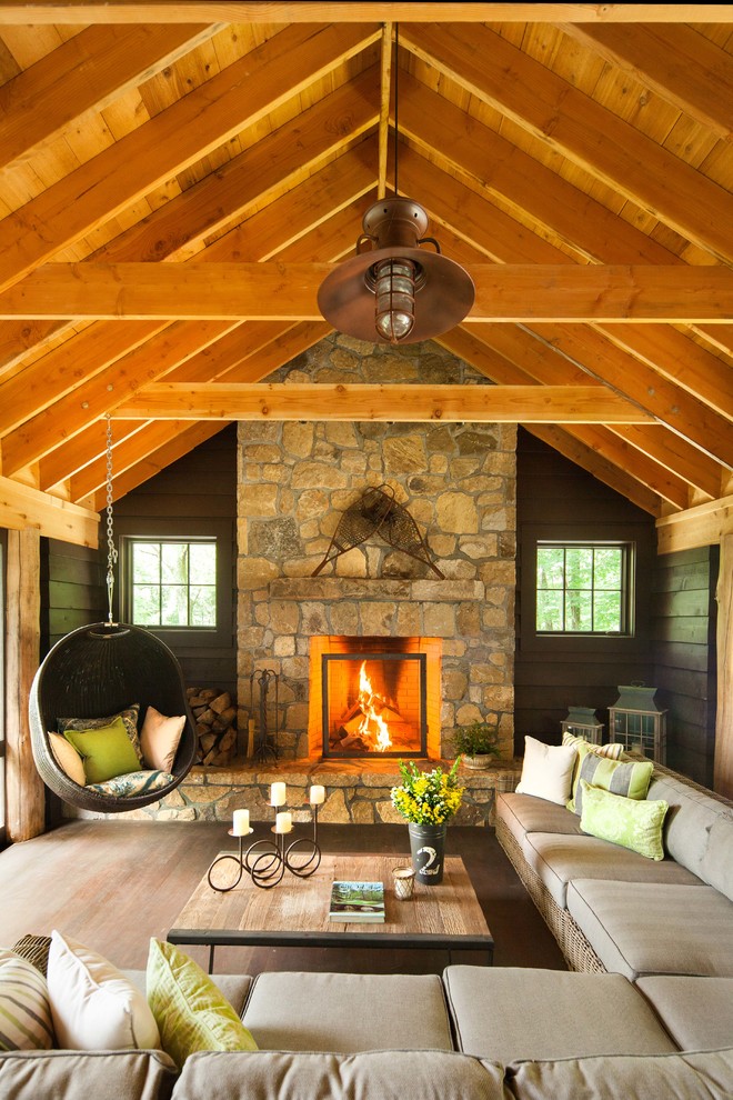 Mountain style living room photo in New York with decking, a roof extension, a standard fireplace and a stone fireplace