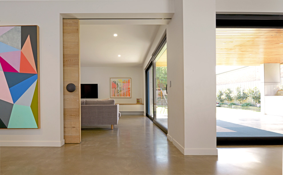 Photo of a large contemporary open concept living room in Geelong with white walls, concrete floors, a wall-mounted tv and grey floor.