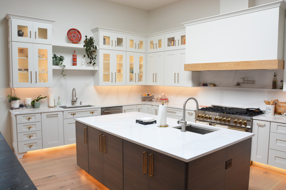 Idéer för att renovera ett mycket stort funkis vit vitt kök, med en undermonterad diskho, luckor med infälld panel, vita skåp, vitt stänkskydd, rostfria vitvaror, mellanmörkt trägolv, flera köksöar och brunt golv