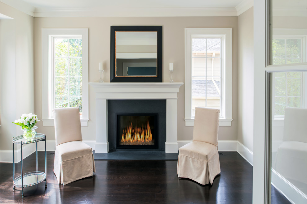 This is an example of a mid-sized traditional formal enclosed living room in DC Metro with beige walls, dark hardwood floors, a standard fireplace and a wood fireplace surround.