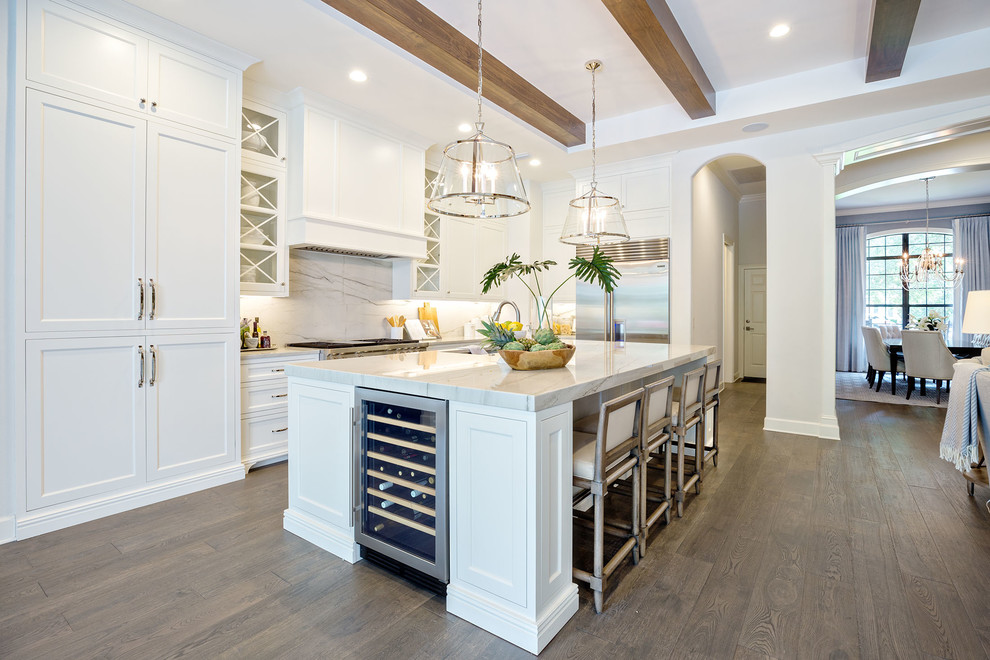 Design ideas for a transitional l-shaped open plan kitchen in Orlando with an undermount sink, shaker cabinets, white cabinets, white splashback, stainless steel appliances, medium hardwood floors, with island and brown floor.