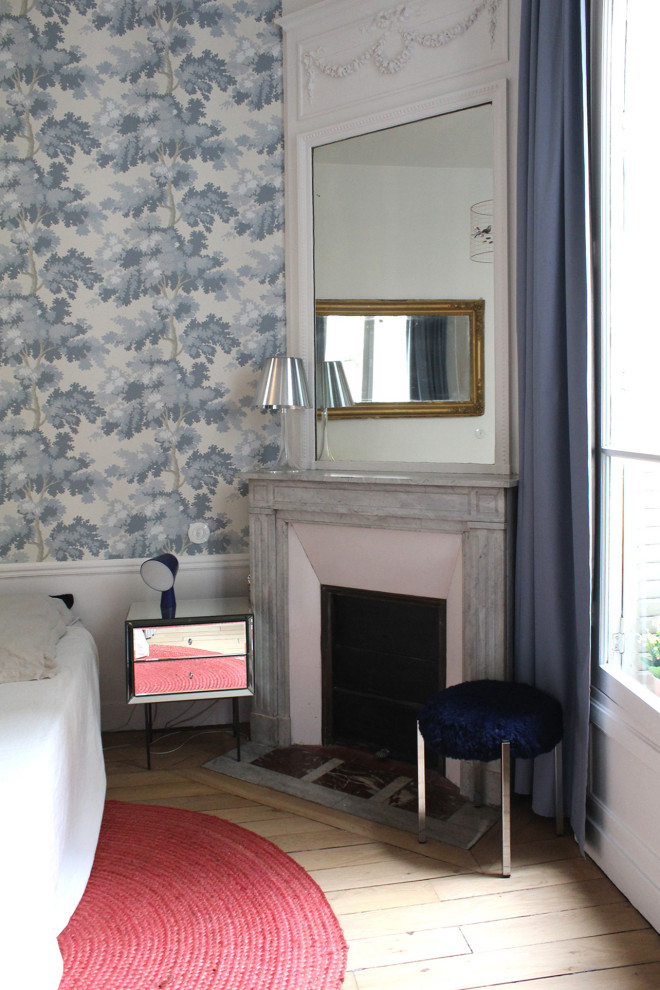 Aménagement d'une chambre parentale haussmannienne classique de taille moyenne avec un mur bleu, parquet clair, une cheminée standard, un manteau de cheminée en carrelage et du papier peint.