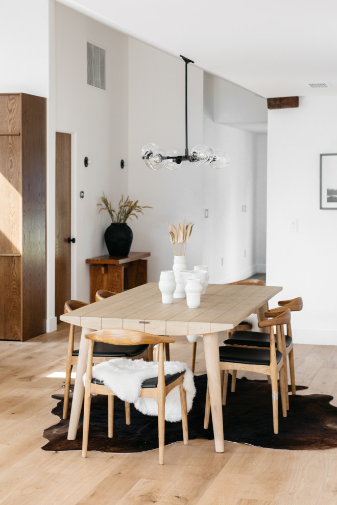 This is an example of a country open plan dining in Los Angeles with white walls, light hardwood floors and beige floor.