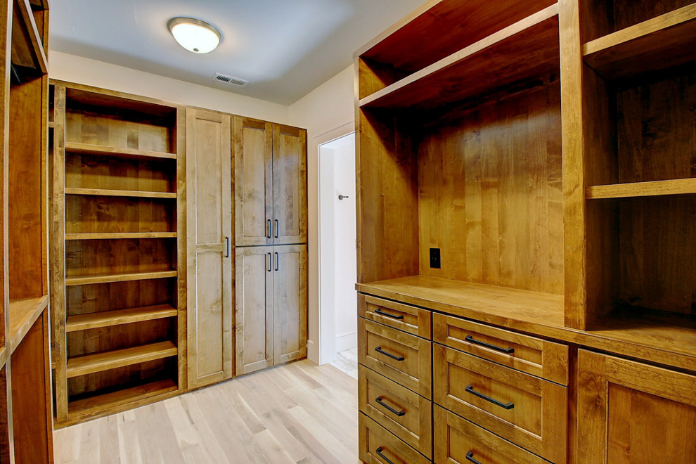 Inspiration for a large transitional gender-neutral walk-in wardrobe in Denver with recessed-panel cabinets, brown cabinets, light hardwood floors and brown floor.