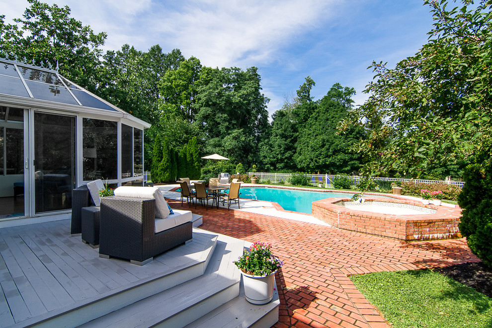This is an example of a large transitional backyard rectangular lap pool in Louisville with a hot tub and brick pavers.