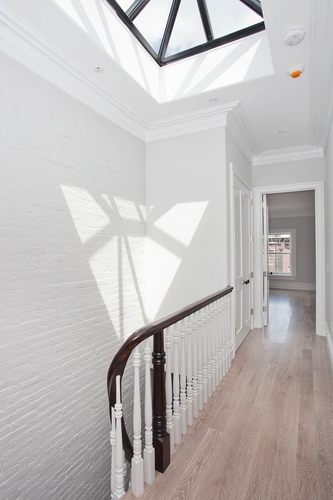 Transitional hallway in New York with white walls and light hardwood floors.