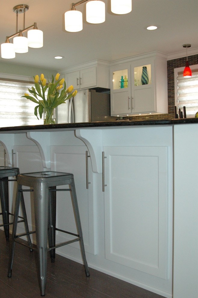 Mid-sized transitional l-shaped medium tone wood floor and brown floor enclosed kitchen photo in Boston with an undermount sink, recessed-panel cabinets, white cabinets, granite countertops, multicolored backsplash, glass tile backsplash, stainless steel appliances and an island
