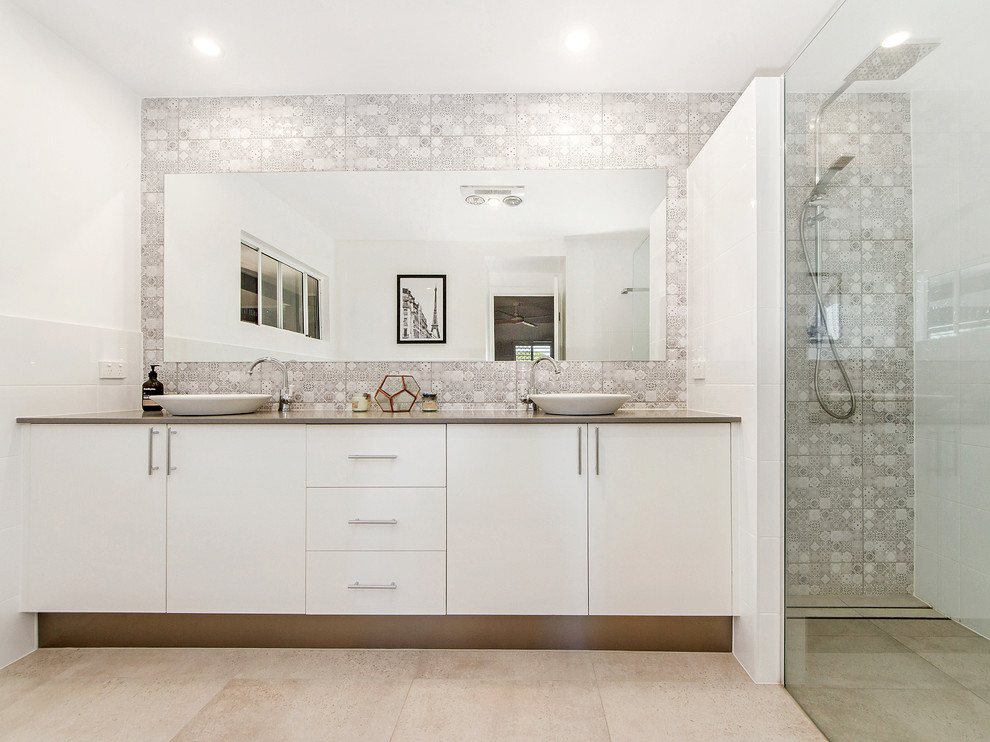 This is an example of a contemporary bathroom in Gold Coast - Tweed with flat-panel cabinets, white cabinets, an alcove shower, gray tile, white tile, white walls, a vessel sink, beige floor and beige benchtops.