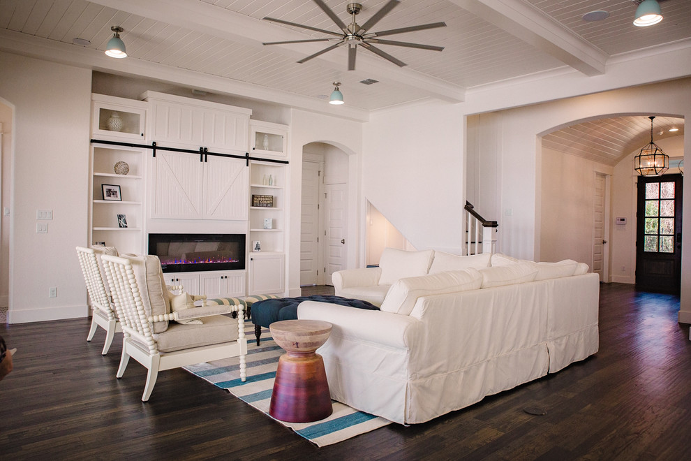 Inspiration for a mid-sized beach style formal open concept living room in Dallas with white walls, dark hardwood floors, a ribbon fireplace, a wood fireplace surround, a concealed tv and brown floor.
