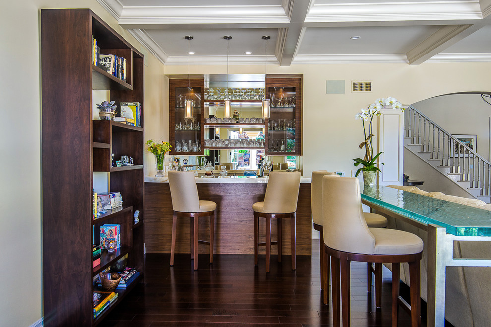 This is an example of a large transitional u-shaped seated home bar in Los Angeles with open cabinets, dark wood cabinets, mirror splashback, dark hardwood floors, brown floor, white benchtop, an undermount sink and onyx benchtops.