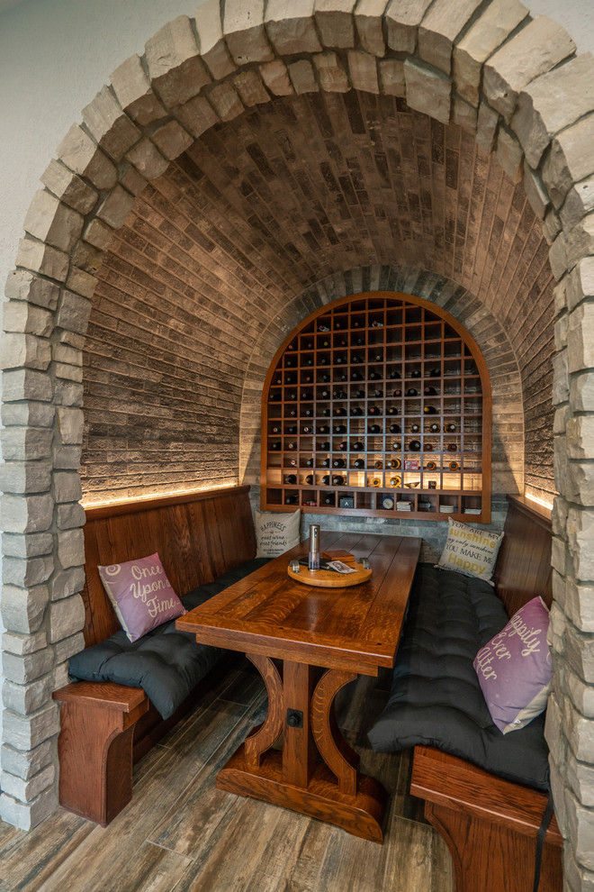 This is an example of a mid-sized mediterranean wine cellar in Detroit with light hardwood floors, storage racks and grey floor.