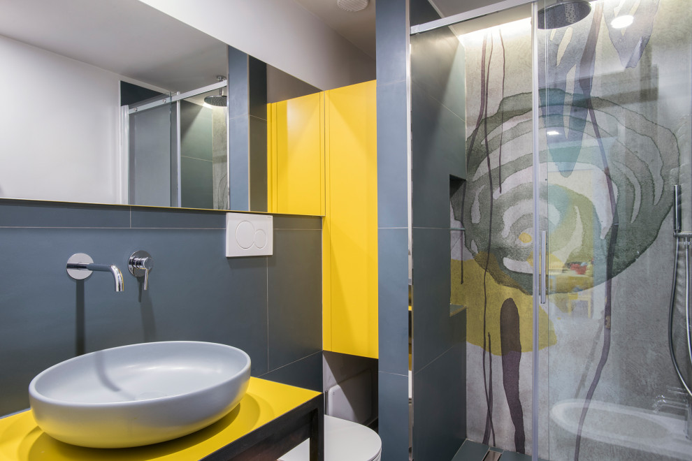 Contemporary 3/4 bathroom in Rome with yellow cabinets, a wall-mount toilet, a vessel sink, a sliding shower screen, yellow benchtops and grey walls.
