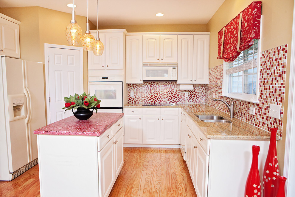 Design ideas for a traditional l-shaped kitchen in Raleigh with a double-bowl sink, raised-panel cabinets, white cabinets, concrete benchtops, red splashback, mosaic tile splashback, white appliances, medium hardwood floors, with island, brown floor and red benchtop.