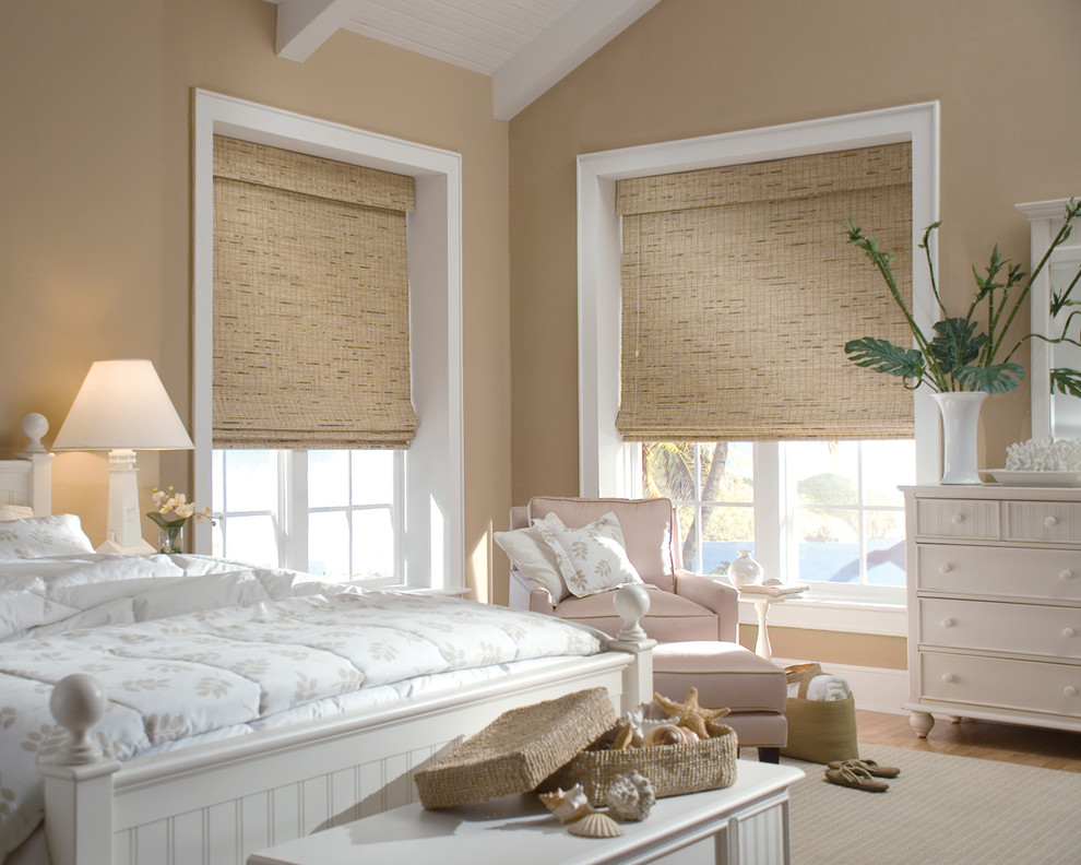 Photo of a large beach style guest bedroom in Houston with beige walls and light hardwood floors.