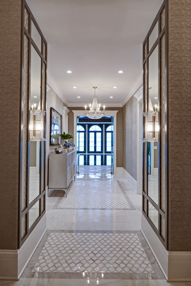 This is an example of a large transitional entry hall in Chicago with white walls, marble floors, white floor and wallpaper.