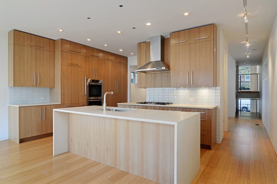 This is an example of an expansive contemporary u-shaped kitchen in Chicago with a single-bowl sink, flat-panel cabinets, light wood cabinets, concrete benchtops, glass tile splashback, stainless steel appliances, bamboo floors and with island.
