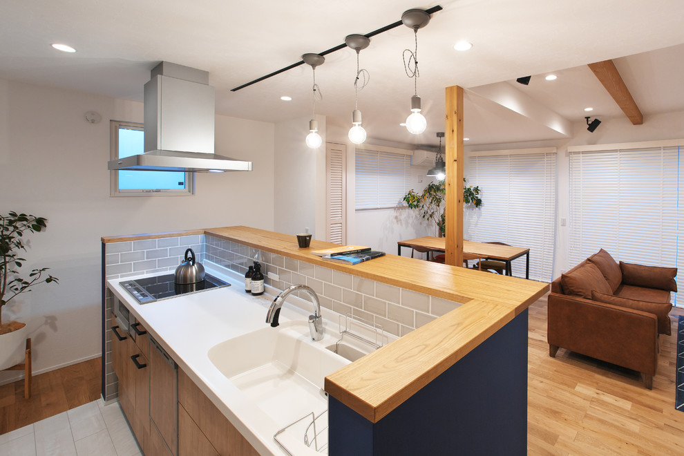 Photo of a large country galley open plan kitchen in Other with flat-panel cabinets, light wood cabinets, solid surface benchtops, with island, white floor, brown benchtop and light hardwood floors.