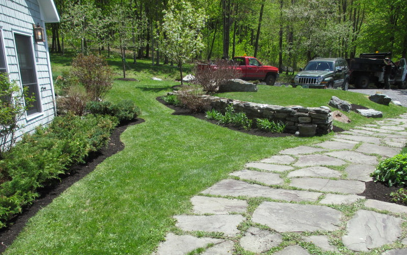 This is an example of a large traditional partial sun side yard mulch retaining wall landscape in Burlington.