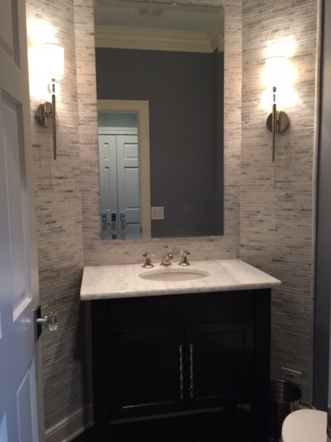 Inspiration for a large transitional powder room in Chicago with recessed-panel cabinets, black cabinets, a two-piece toilet, gray tile, matchstick tile, white walls, dark hardwood floors, an undermount sink, quartzite benchtops, brown floor and white benchtops.