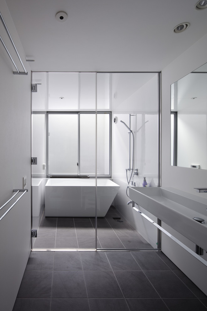 Photo of a contemporary 3/4 wet room bathroom in Other with a freestanding tub, white walls, a trough sink, grey floor and an open shower.