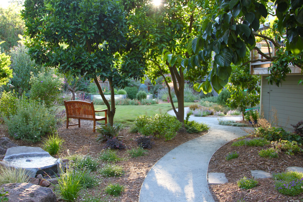 На фото: весенний засухоустойчивый сад среднего размера на заднем дворе в стиле кантри с клумбами, полуденной тенью, покрытием из каменной брусчатки и с деревянным забором с