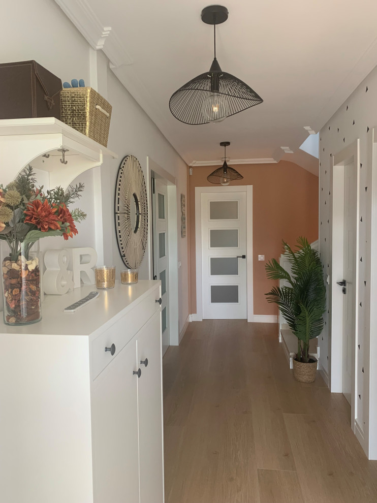 Modelo de entrada tradicional renovada de tamaño medio con paredes blancas, suelo de madera clara, puerta simple y puerta blanca