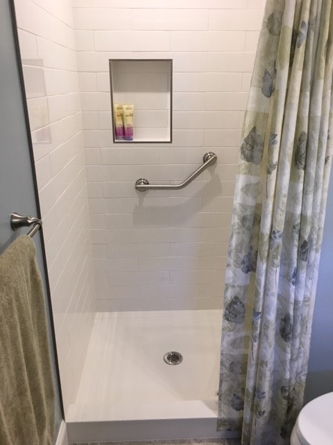 Mid-sized beach style master bathroom in Other with raised-panel cabinets, white cabinets, an alcove shower, a two-piece toilet, white tile, subway tile, blue walls, porcelain floors, an undermount sink, solid surface benchtops, grey floor and a shower curtain.