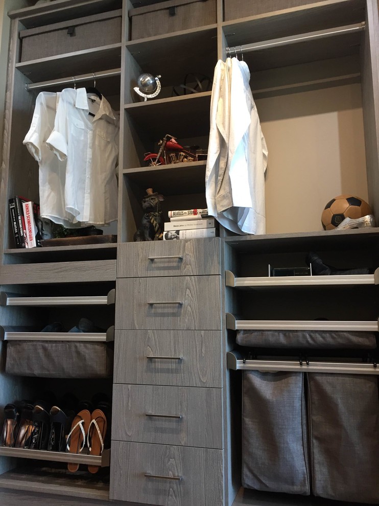 Photo of a mid-sized transitional gender-neutral walk-in wardrobe in Vancouver with flat-panel cabinets and grey cabinets.