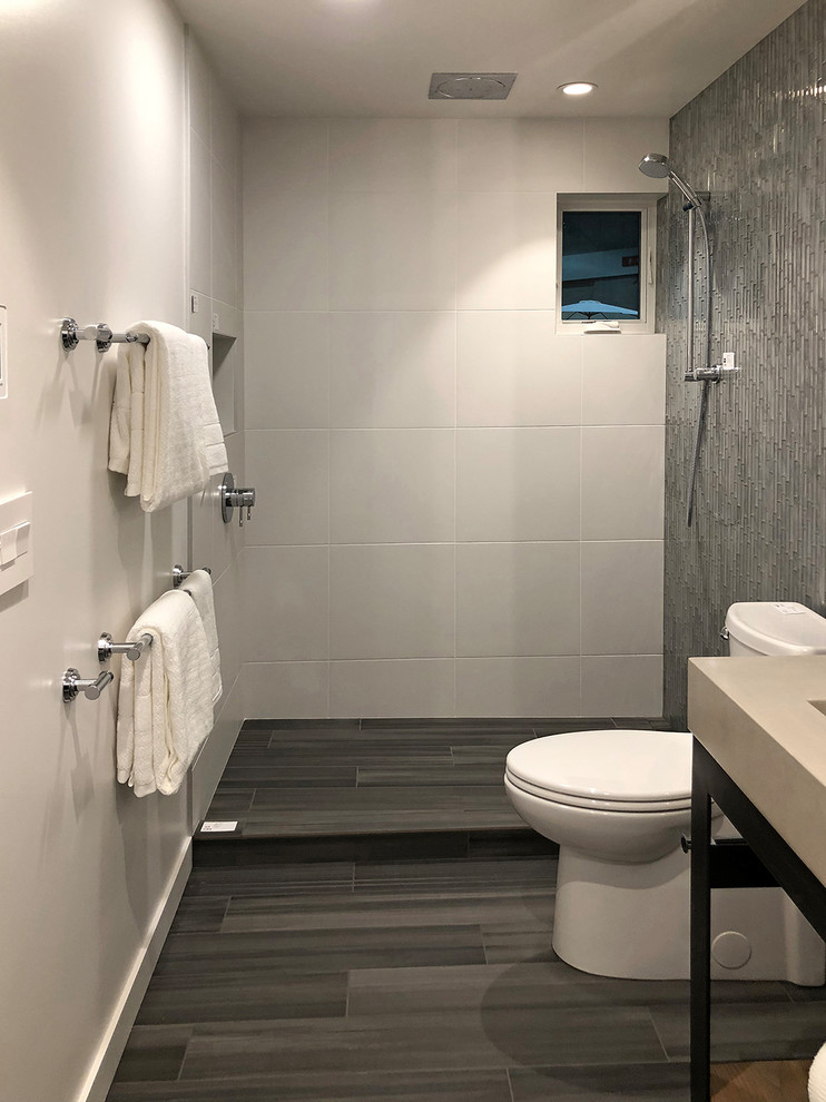 Photo of a small contemporary kids bathroom in Los Angeles with furniture-like cabinets, dark wood cabinets, a drop-in tub, an open shower, a one-piece toilet, white tile, porcelain tile, white walls, porcelain floors, an integrated sink, concrete benchtops, grey floor and a hinged shower door.