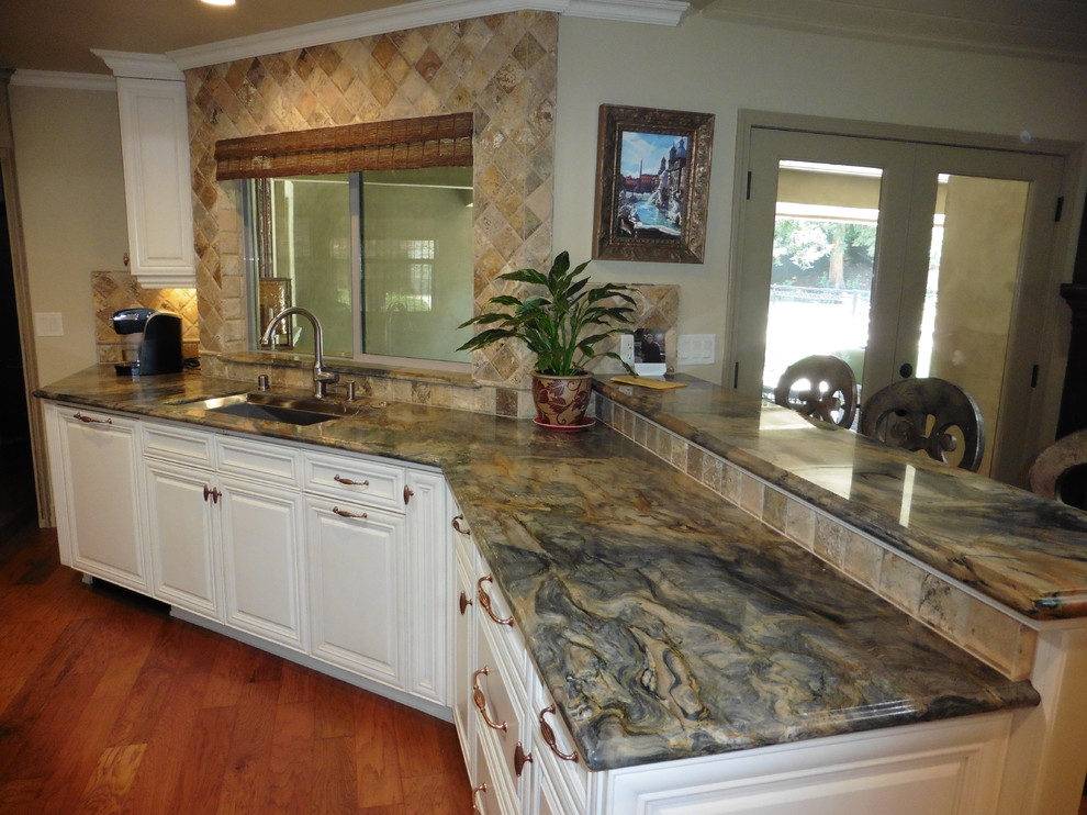 Large transitional medium tone wood floor and brown floor kitchen photo with an undermount sink, raised-panel cabinets, white cabinets, brown backsplash, stone tile backsplash, paneled appliances and a peninsula
