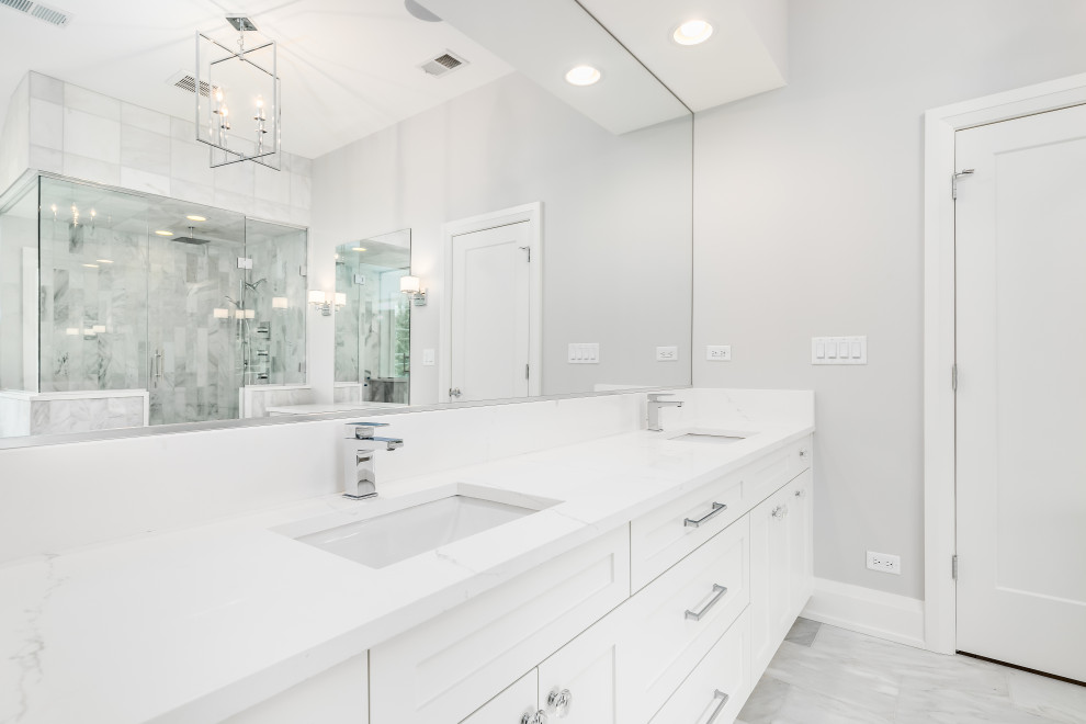 Cette image montre une grande salle de bain principale minimaliste avec un placard à porte affleurante, des portes de placard blanches, une douche à l'italienne, un carrelage blanc, du carrelage en marbre, un mur blanc, un sol en marbre, un lavabo encastré, un plan de toilette en marbre, un sol gris, une cabine de douche à porte battante, un plan de toilette blanc, meuble double vasque et meuble-lavabo suspendu.