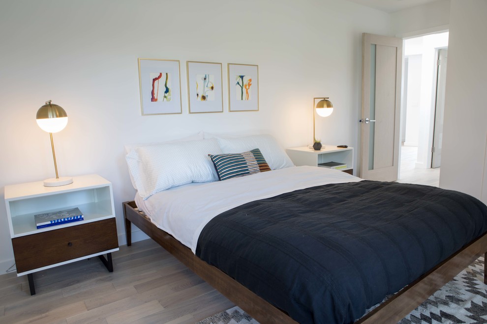 Design ideas for a mid-sized modern guest bedroom in Los Angeles with white walls, light hardwood floors and brown floor.