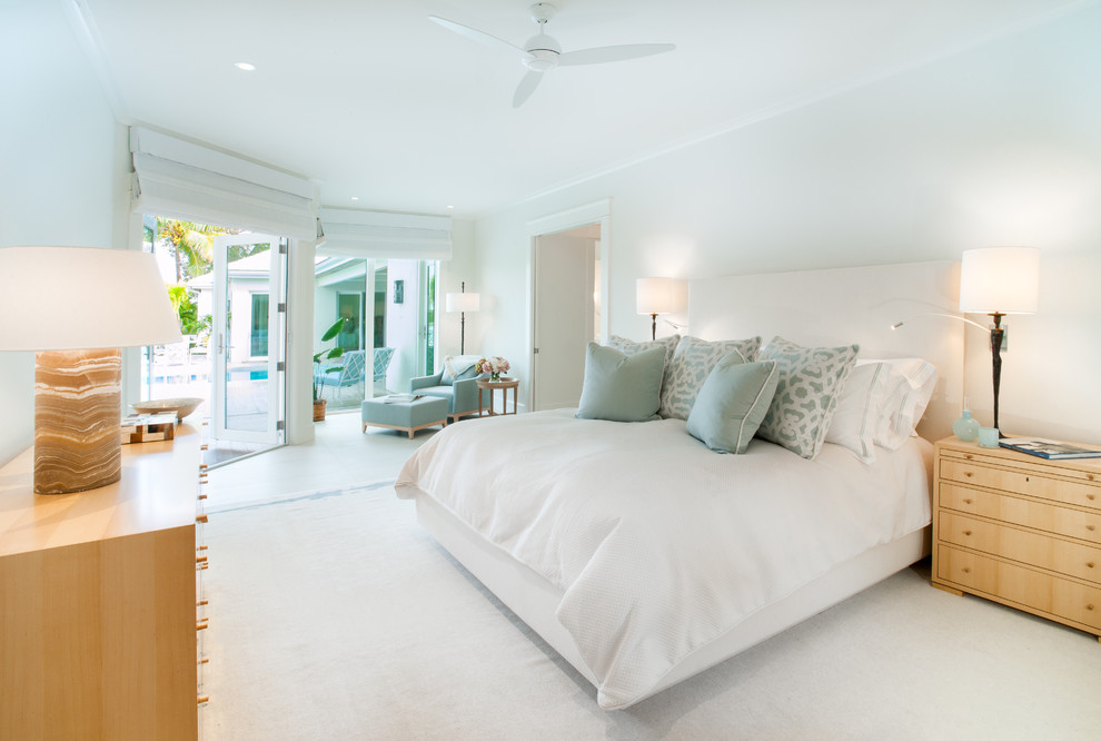 This is an example of a large beach style master bedroom in Tampa with white walls, porcelain floors and no fireplace.