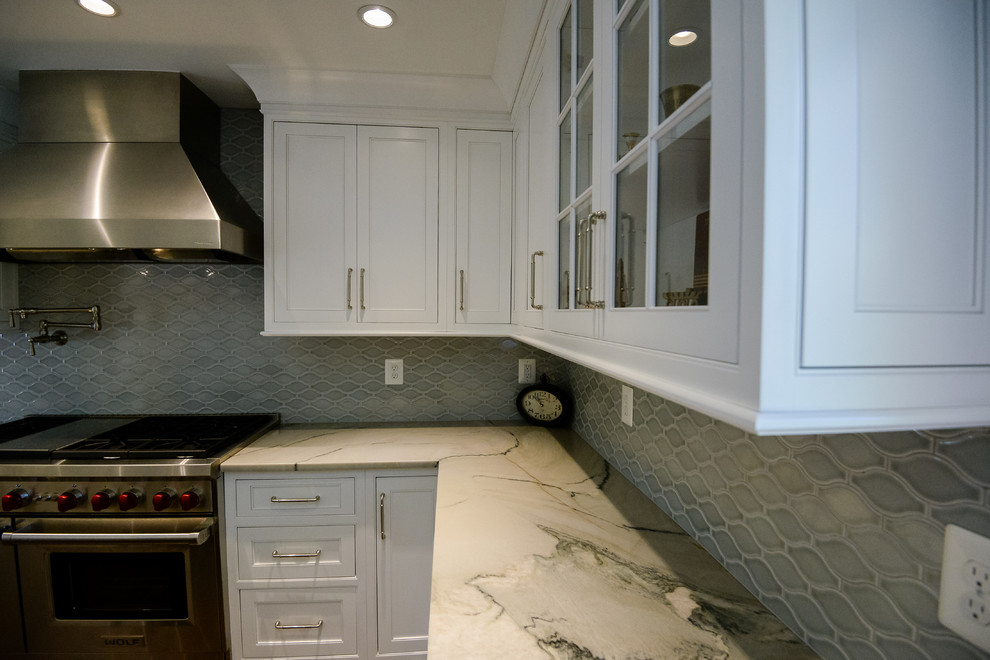 Large transitional u-shaped medium tone wood floor and brown floor eat-in kitchen photo in DC Metro with a farmhouse sink, recessed-panel cabinets, white cabinets, marble countertops, stainless steel appliances, an island, gray backsplash and porcelain backsplash