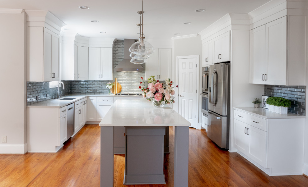 Foto på ett mellanstort funkis vit kök, med en undermonterad diskho, skåp i shakerstil, vita skåp, bänkskiva i kvarts, grått stänkskydd, glaspanel som stänkskydd, rostfria vitvaror, mellanmörkt trägolv, en köksö och orange golv