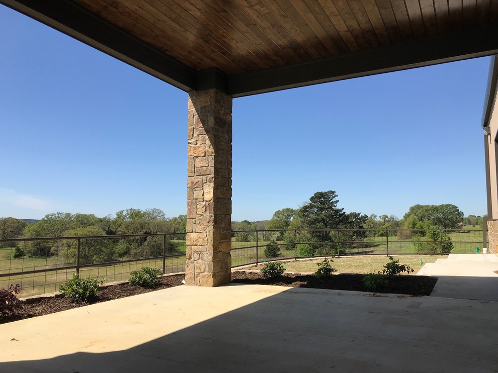 Photo of a large country backyard patio in Dallas with an outdoor kitchen, concrete slab and a roof extension.