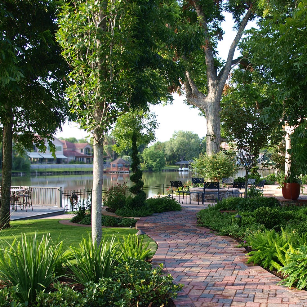 Inspiration for an expansive traditional sloped partial sun garden in Houston with a garden path and brick pavers.